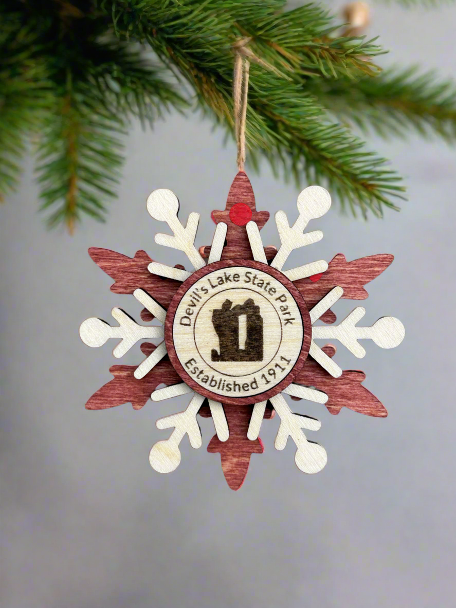 Red wood snowflake ornament with text Devil's Lake State Park and Devil's Rock symbol.
