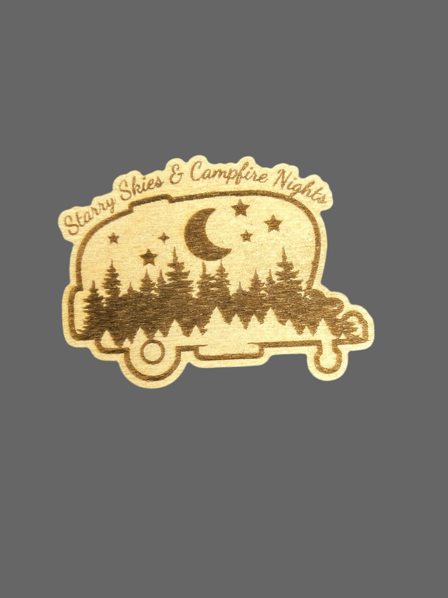 Wood magnet in the shape of a camper with a forest and starry night design and the text "starry Skies and Campfire Nights".