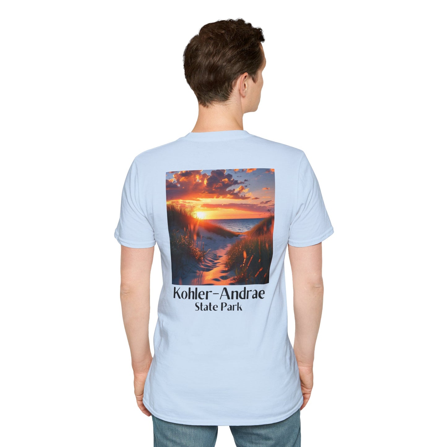 Male Model wearing a light blue t-shirt featuring a back design of looking through the sand dunes at a colorful sunrise over Lake Michigan and the text: Kohler-Andrae State Park.