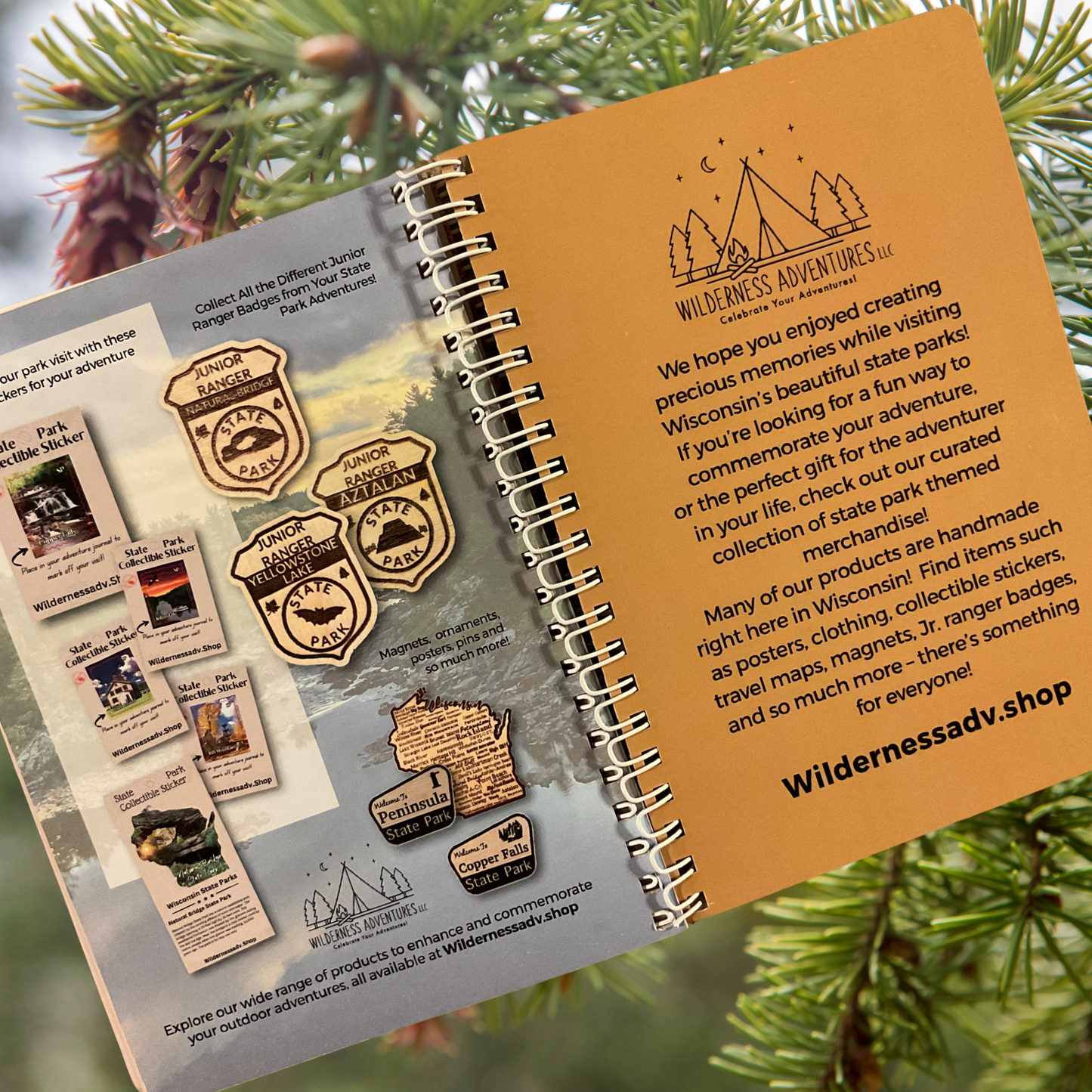Wisconsin State Parks, Forests, and Trails Interactive Guide. Featuring a display of inside pages of collectible gifts available for purchase. Photo background: evergreen boughs and cones.