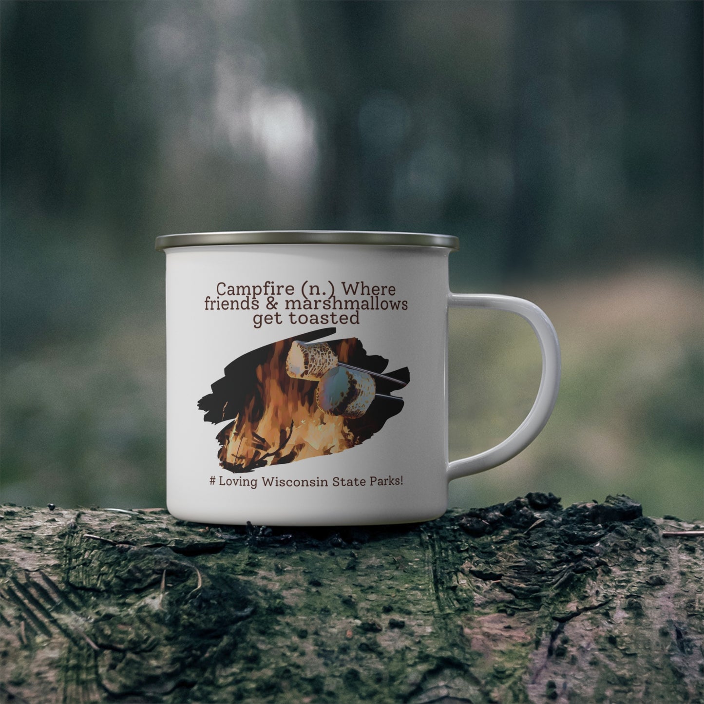 White enamel camper mug on a log with a graphic design of a marshmallow being roasted over a fire and the text: campfire (n.) where friends and marshmallows get toasted. # loving Wisconsin State Parks”.