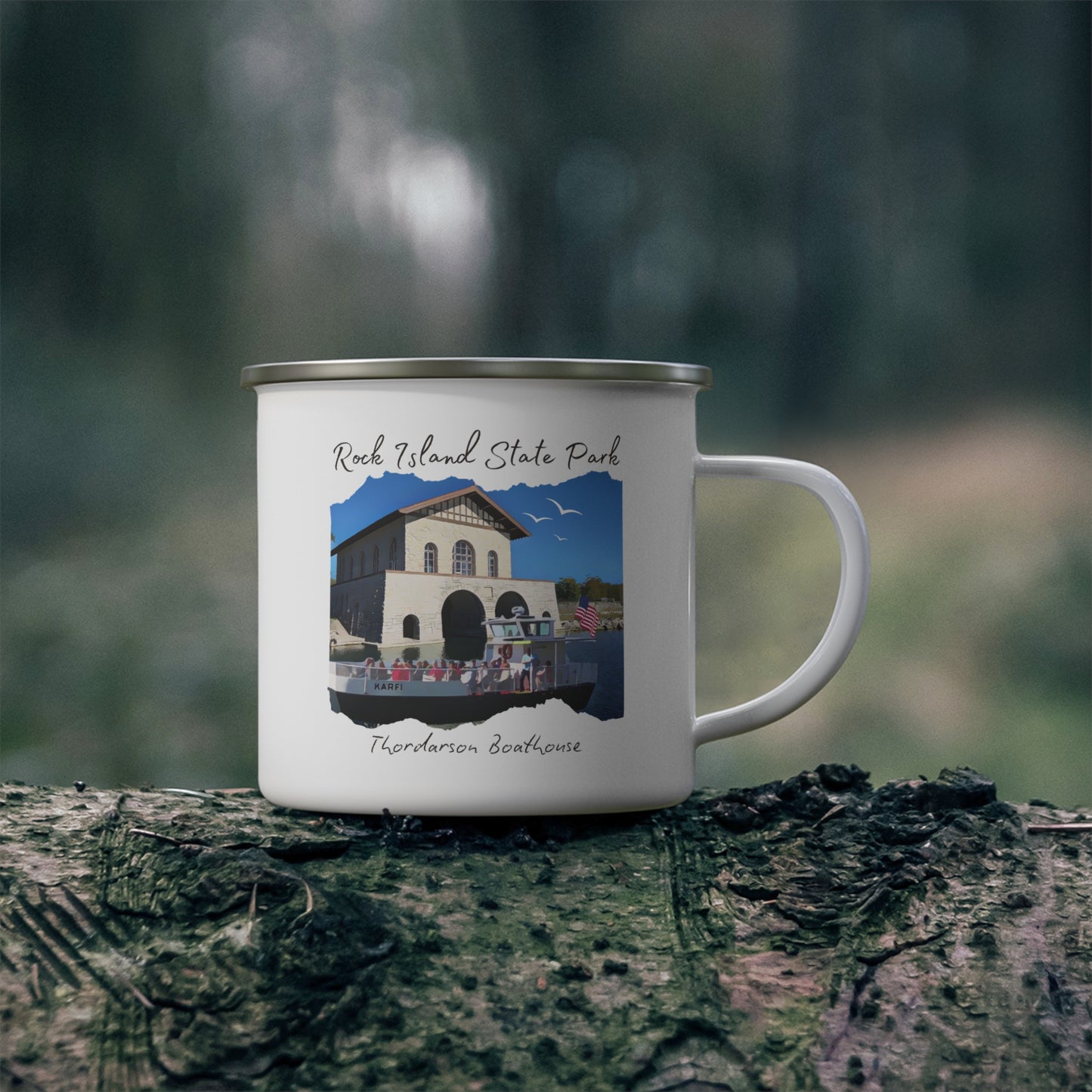 White enamel campfire mug depicting a scene of a ferry boat pulling up to the stone boat house on Rock Island. Photo background: mug sitting on a log in the woods.