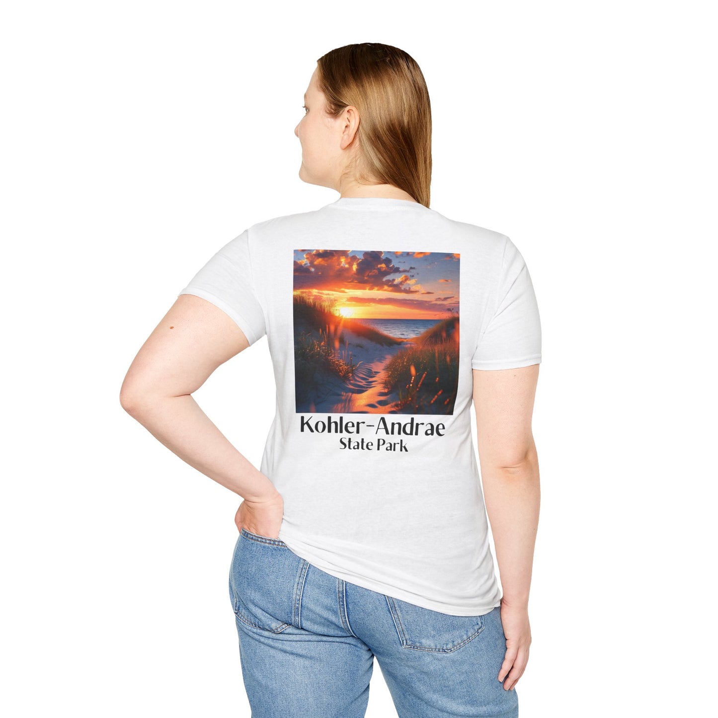 Female model wearing a white t-shirt featuring a back design of looking through the sand dunes at a colorful sunrise over Lake Michigan and the text: Kohler-Andrae State Park.