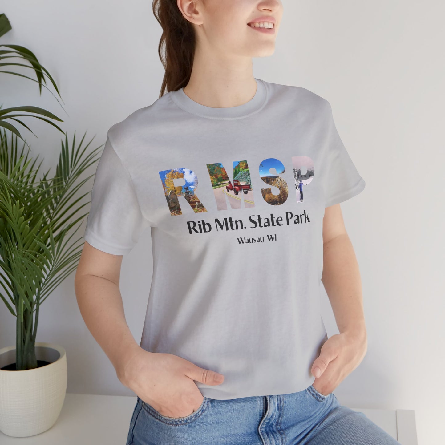 Female model wearing a athletic gray RMSP shirt depicting the letters RMSP, each with a different park scene.