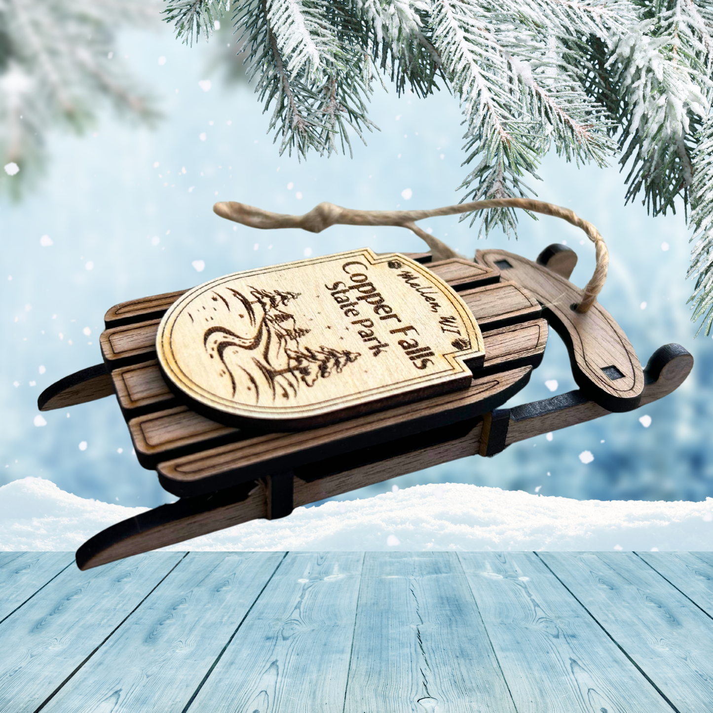 Wooden sled ornament with 'Copper Falls State Park' label against a snowy background