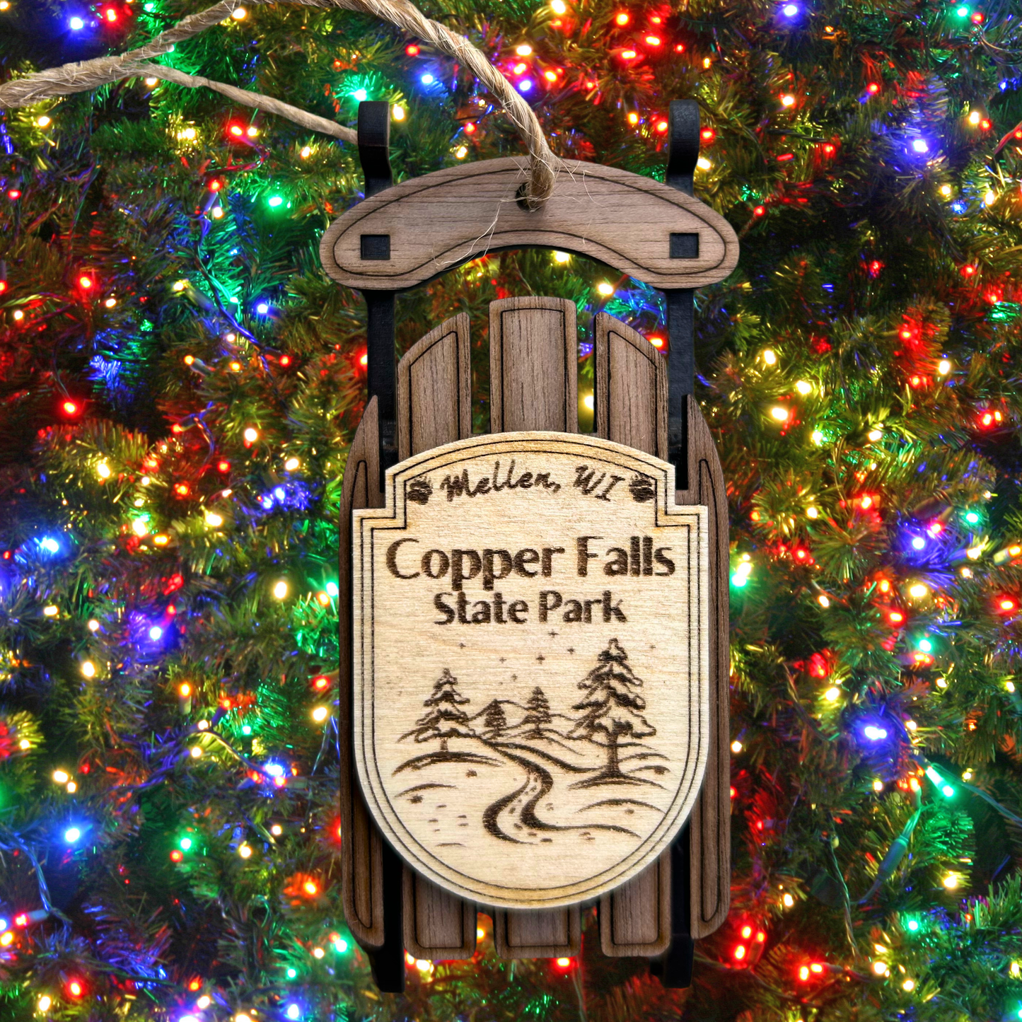 Wooden ornament with 'Copper Falls State Park' text and design, hanging on a Christmas tree.