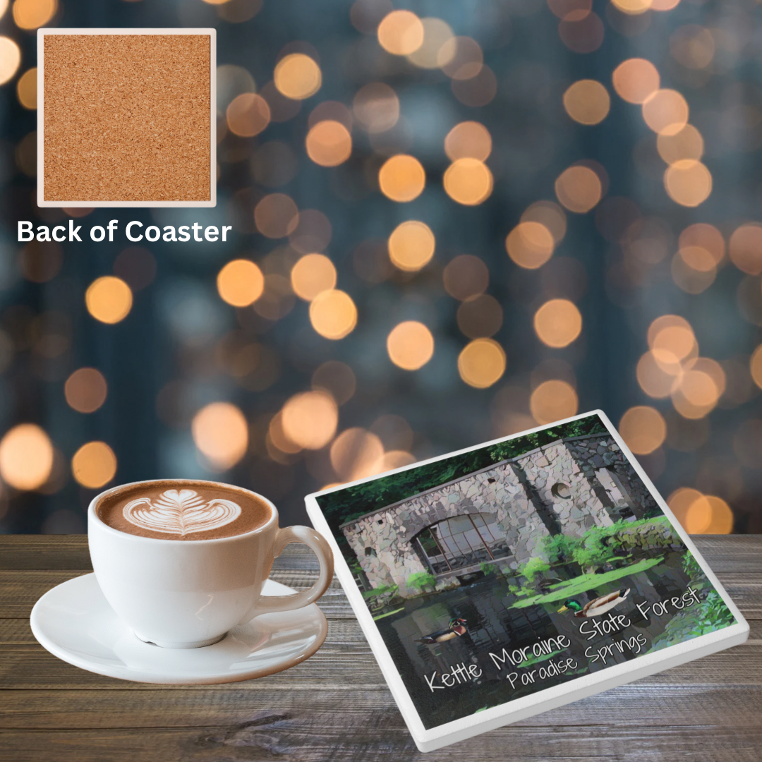 Ceramic Coaster featuring the stone spring house at Paradise Springs. Features the text “Kettle Moraine State Forest Paradise Springs.” Photo background: coaster on a wood table next to a coffee cup.