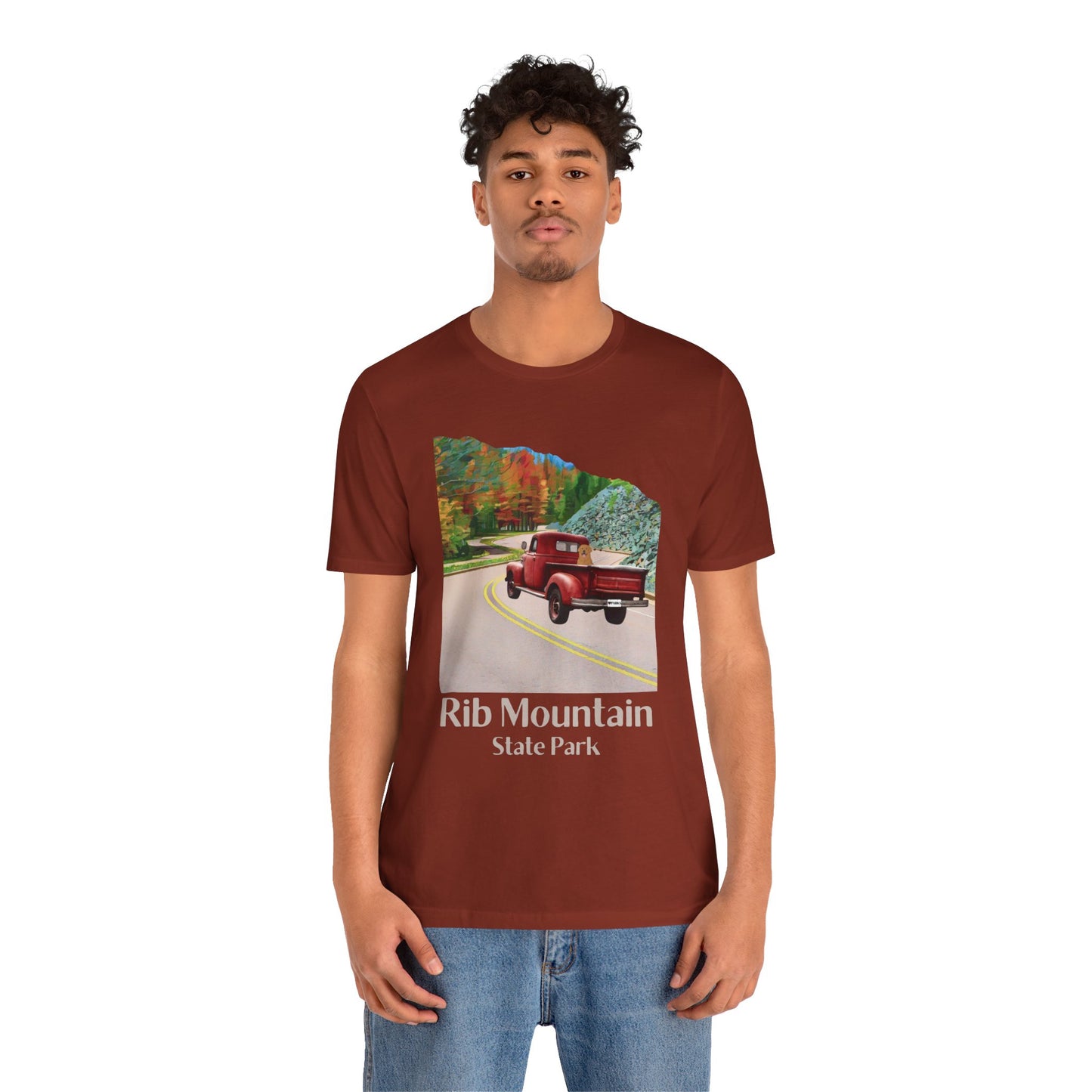 Male model wearing Rust colored T-shirt with vintage truck driving up the road to Rib Mountain State Park during fall leaf color graphic.