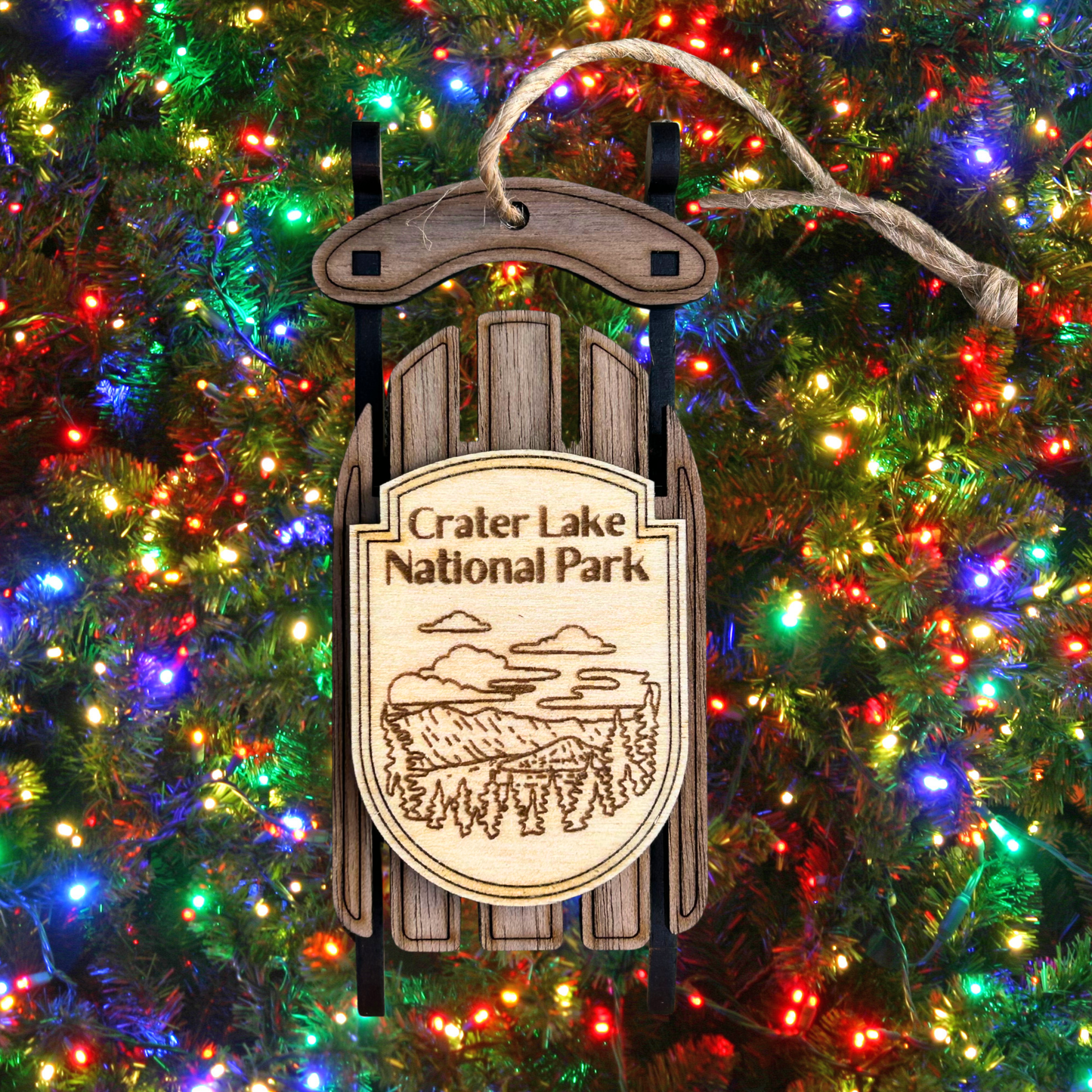 Decorative sign for Crater Lake National Park on a Christmas tree with lights.