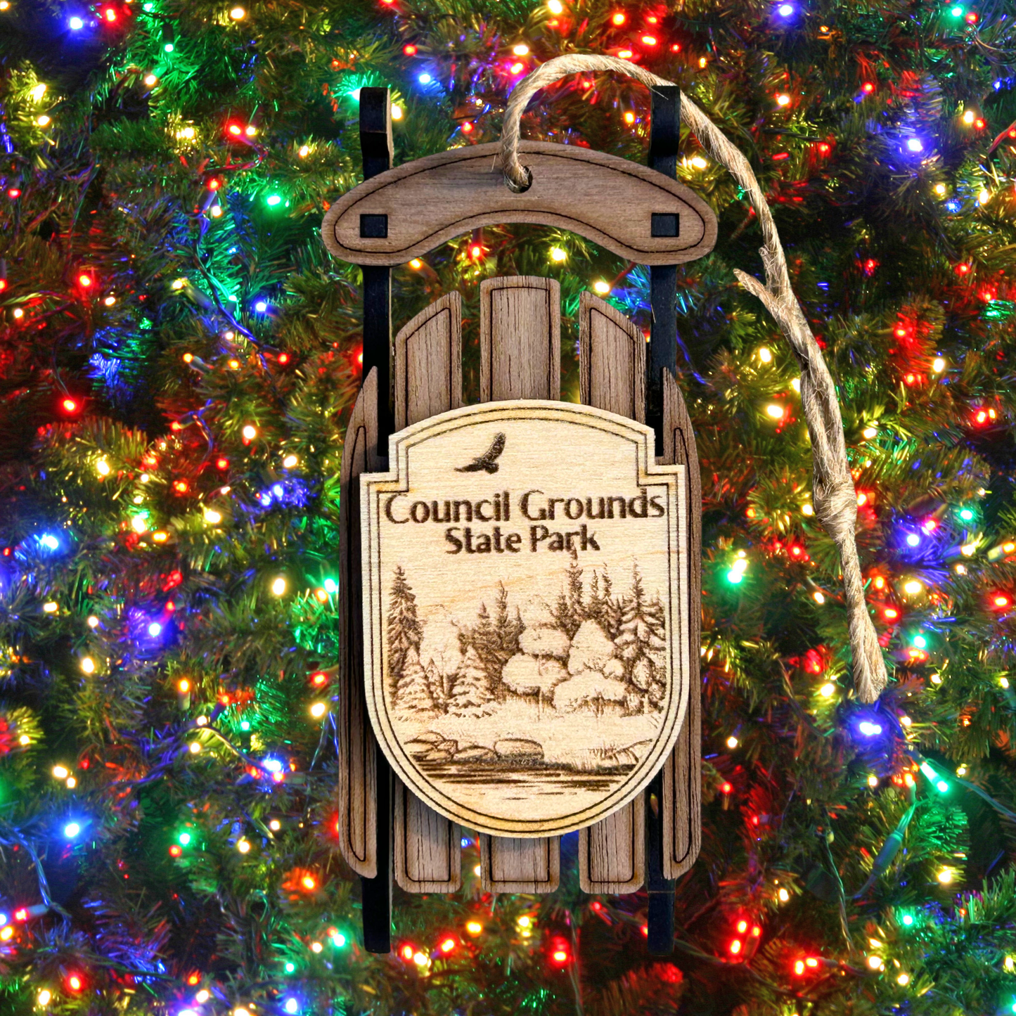 Wooden sled ornament with 'Council Grounds State Park' text on a Christmas tree with lights.