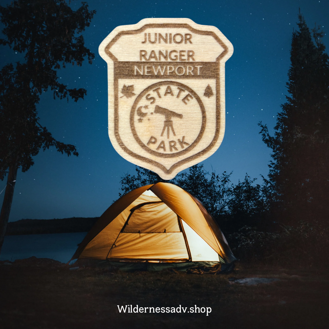 Wood Jr. Ranger badge with the text: Junior Ranger Newport State Park. Photo background of a starry sky and a tent.