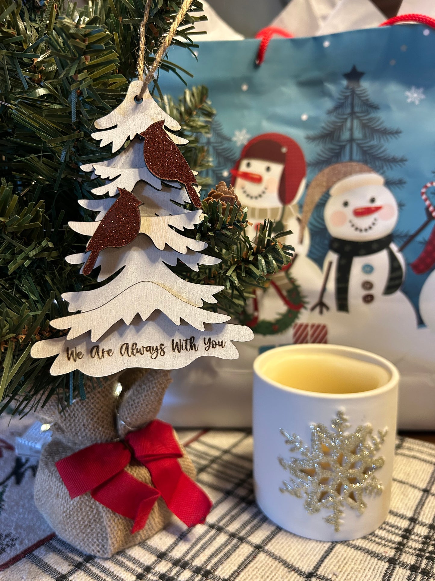 Two red glitter colored cardinals on a wood tree ornament with the text “we are always with you.”