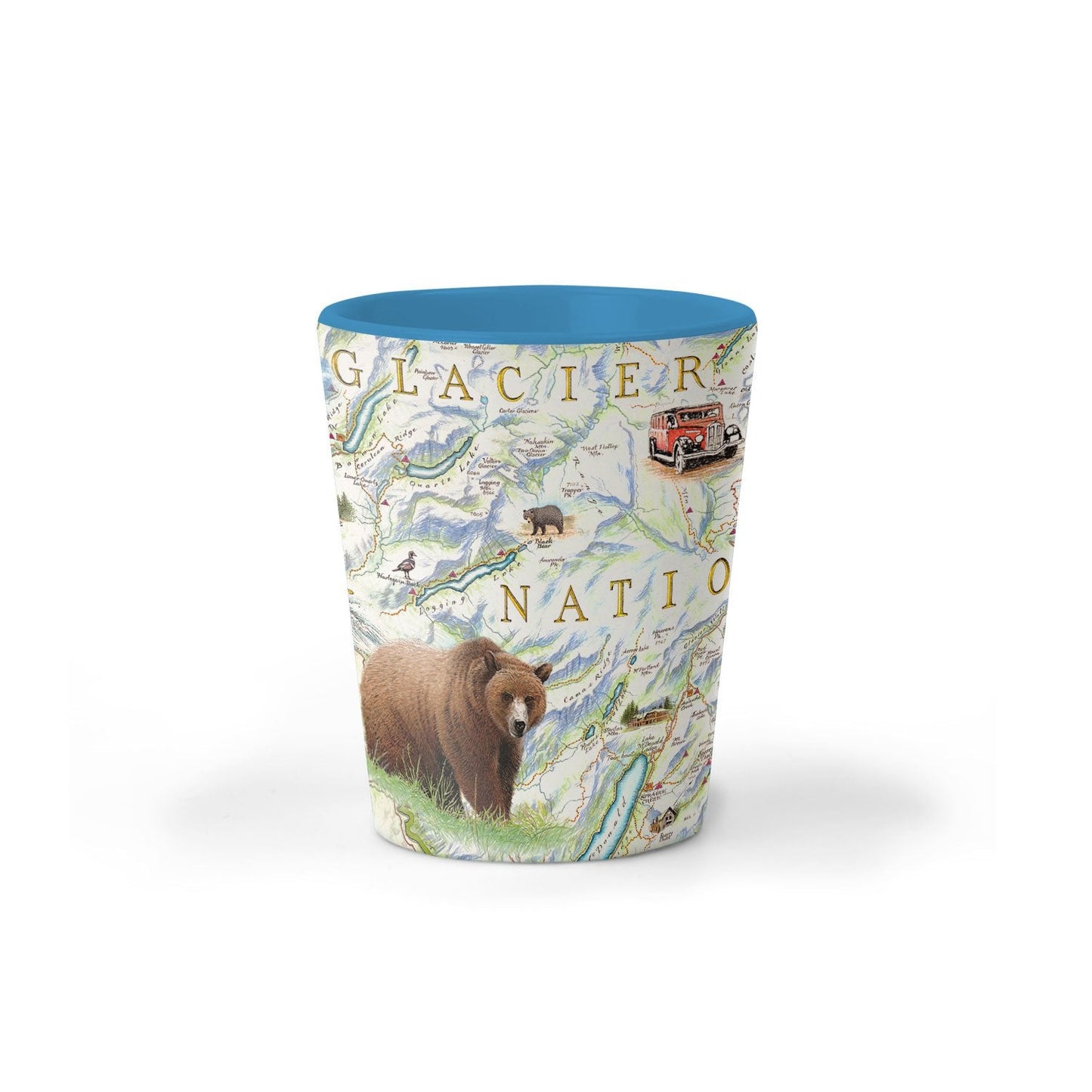 A cylindrical shot glass featuring a Glacier National Park map design with a brown grizzly bear, green hills, and a bright blue interior rim, shown on a white background.