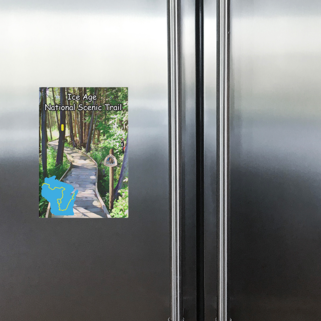 Metal button magnet depicting a boardwalk through the woods and a map showing the route of the Ice Age Trail. Photo background: stainless steel refrigerator doors.