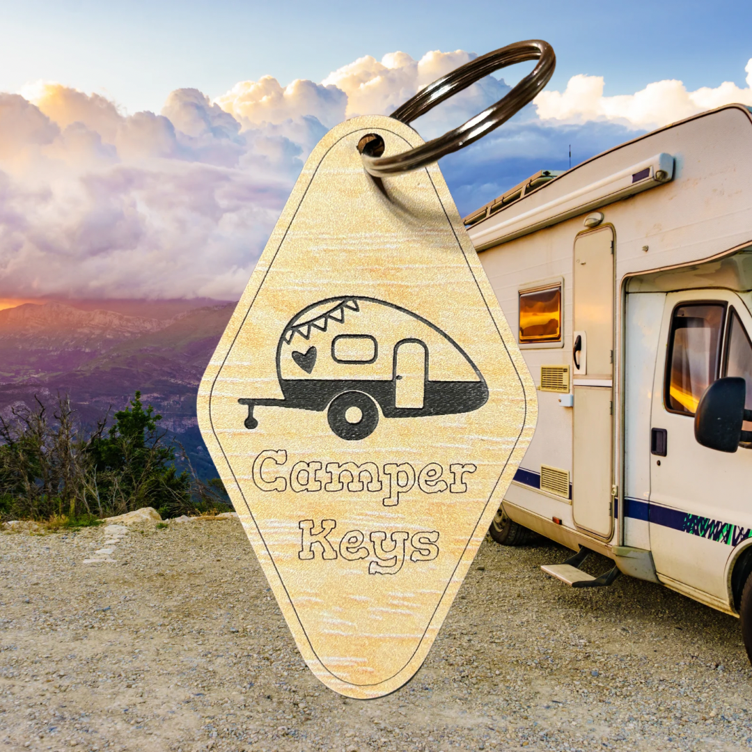 Wood grain acrylic keychains with camper icon and text “camper keys”. Photo background: RV parked at overlook with distant mountains at sunset.