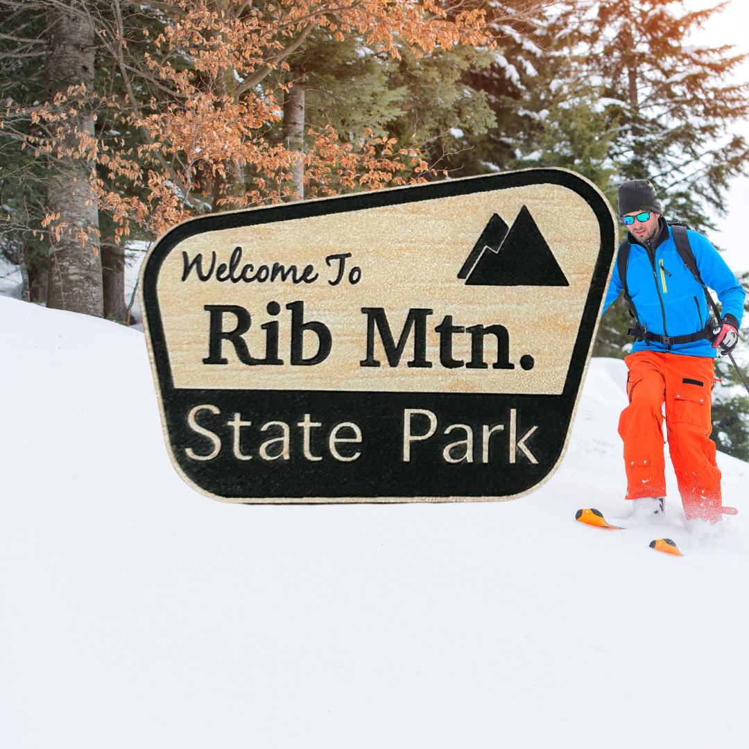 Wood grain acrylic magnet with “welcome to Rib Mtn. State Park” and mountain icon. Photo background: downhill skier skiing down a hill.