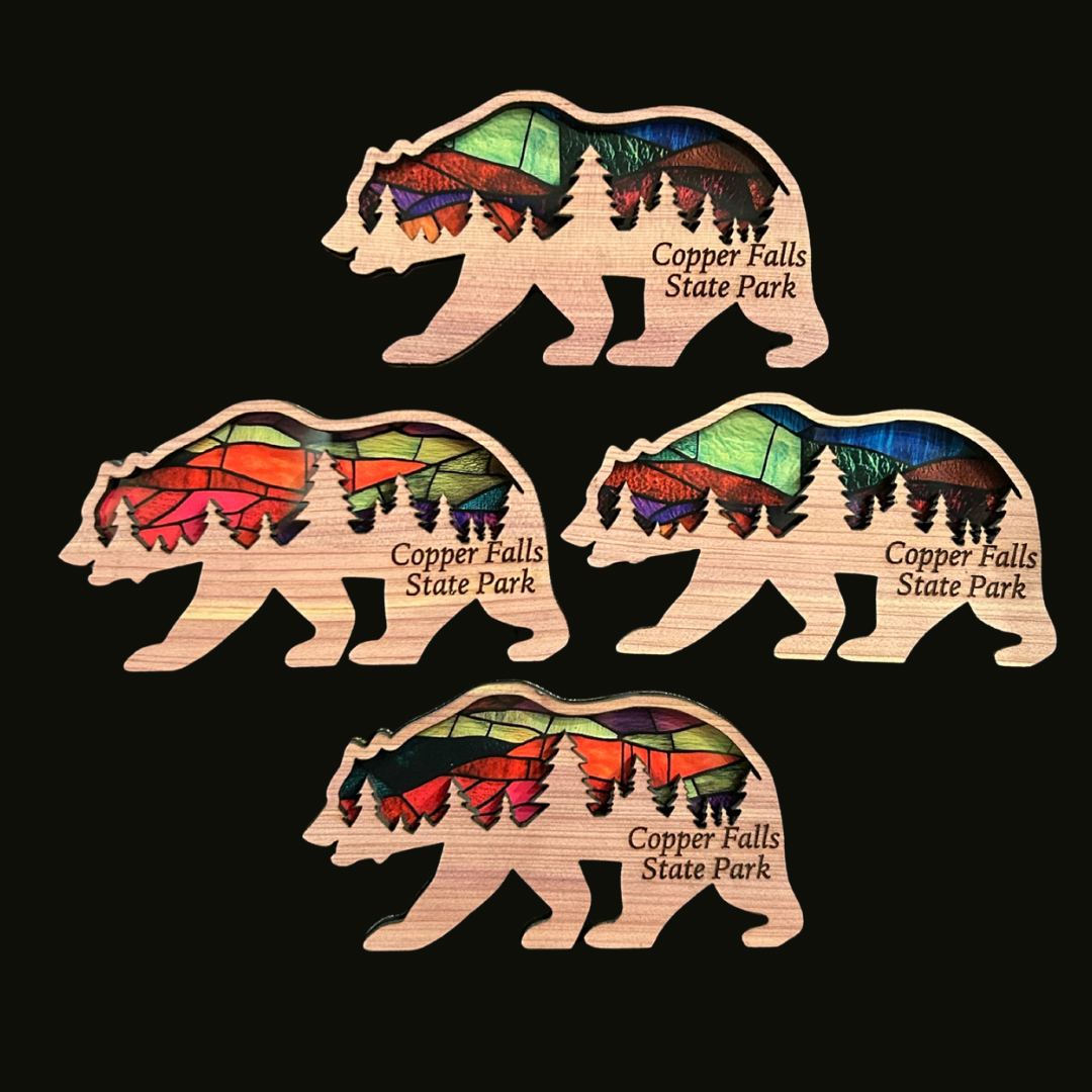 Four cedar bear shaped magnets with a faux stained glass appearance on a black background.