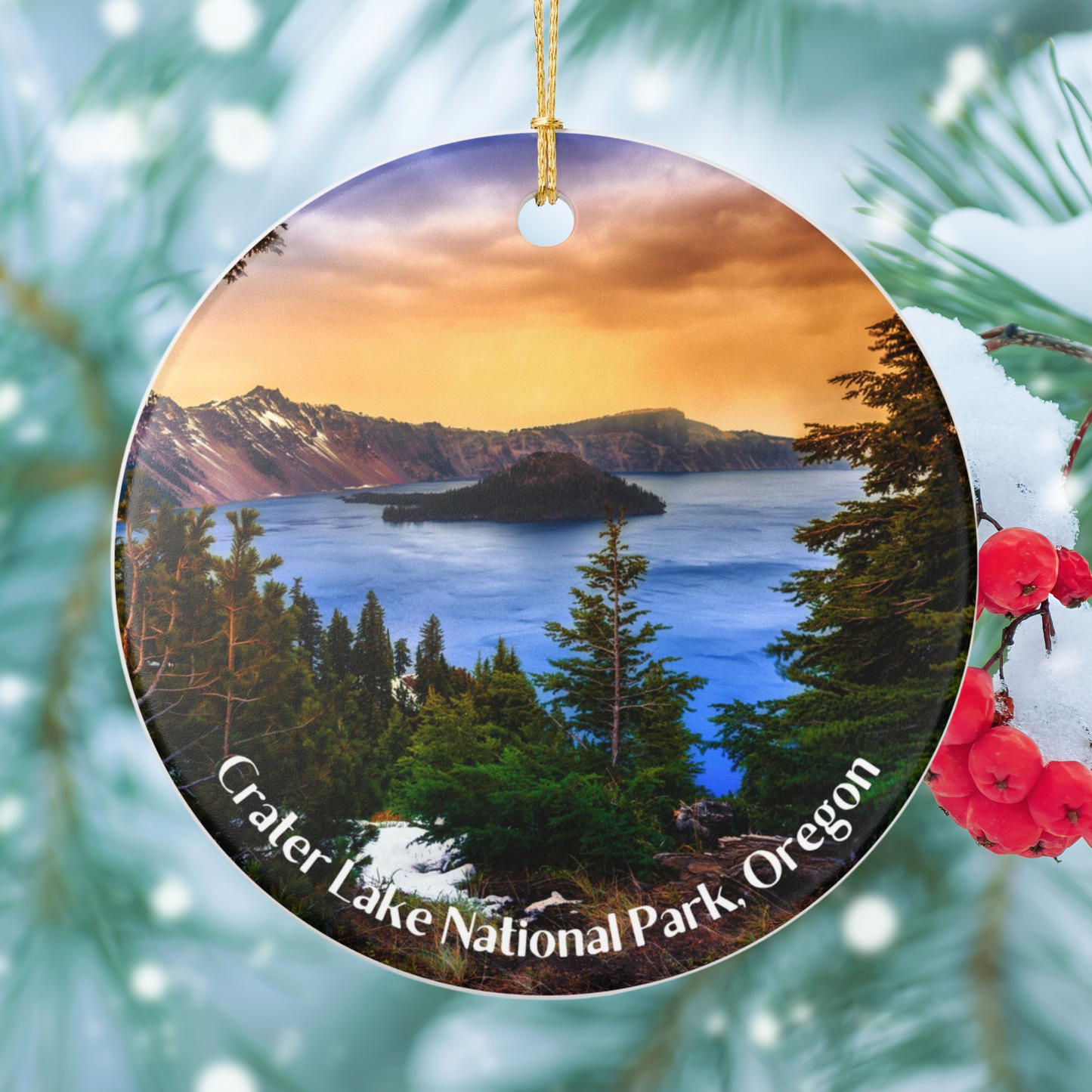 Round ceramic ornament featuring a vivid sunrise over Crater Lake design. Photo background: snow covered tree.