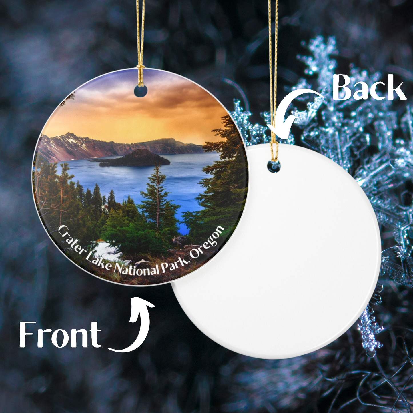 Photo showing the front of a Round ceramic ornament featuring a vivid sunrise over Crater Lake design, and the plain reverse side of ornament. Photo background: closeup of a snowflake.