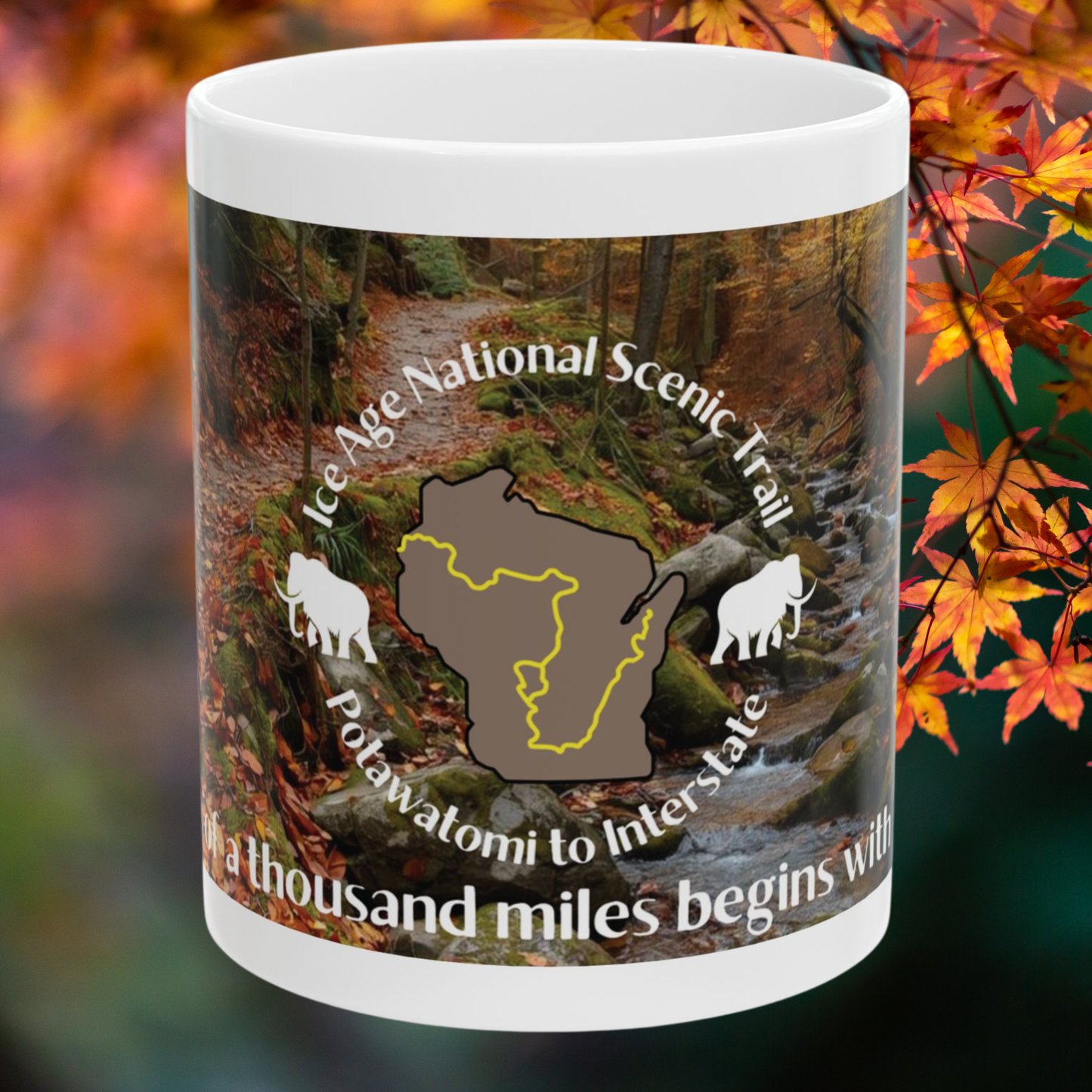 Mug with Ice Age National Scenic Trail design against a blurred autumn leaf background