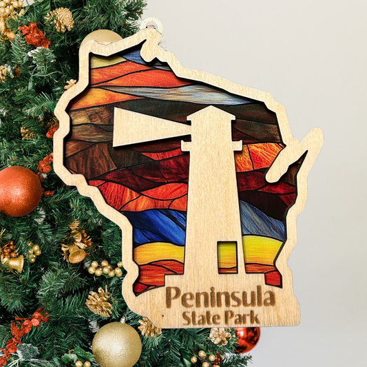 Wood Wisconsin Shaped ornament with a stained glass look and a lighthouse.  Includes the text: Peninsula State Park. Photo Background: Christmas tree.