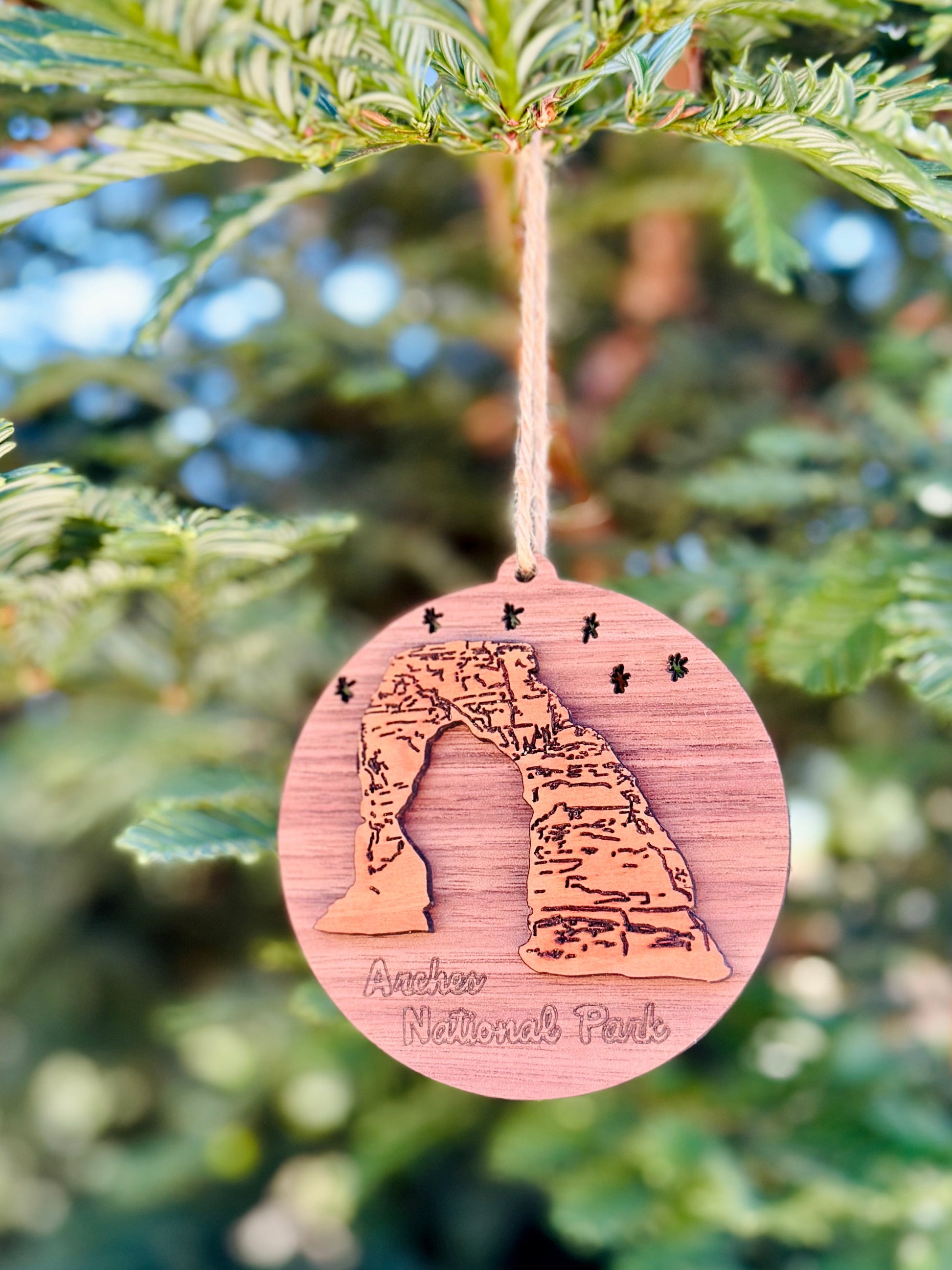 Wooden ornament with Arches National Park design hanging on a tree