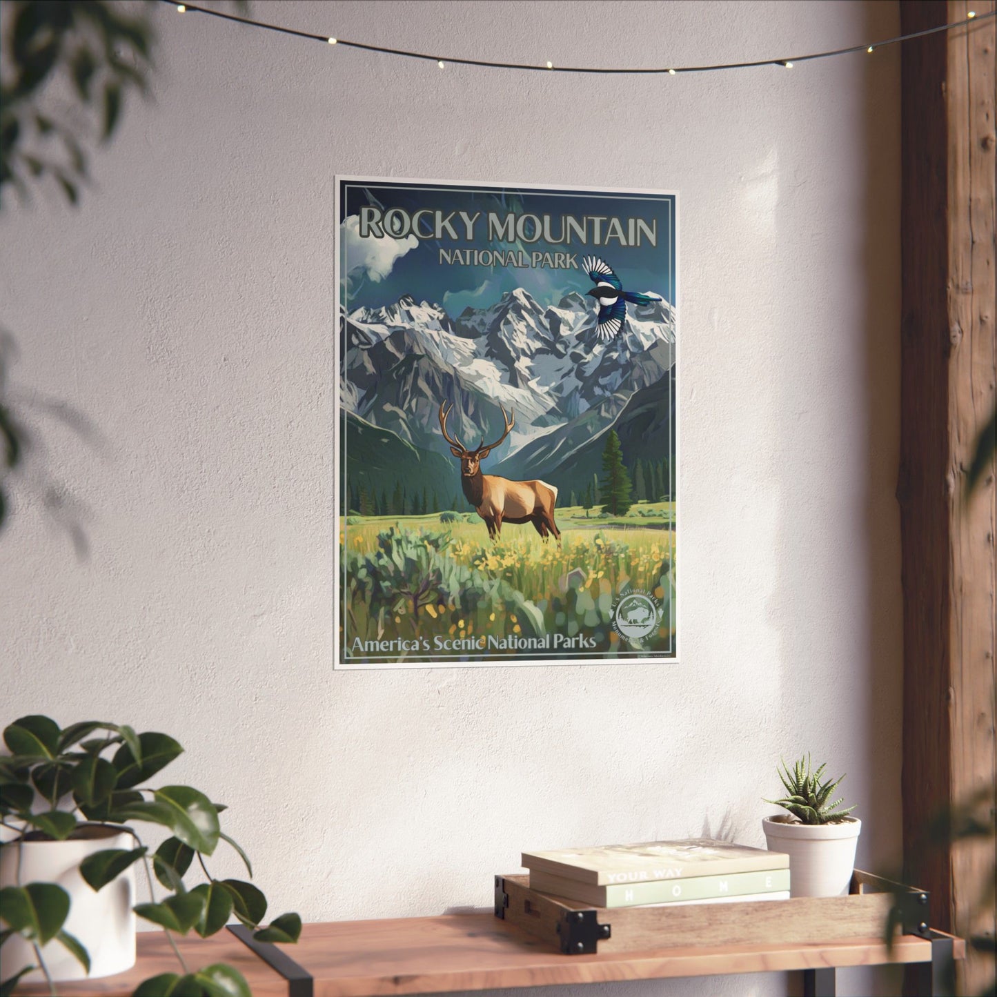 Poster of Rocky Mountain National Park hanging on a wall above a wooden shelf with plants.