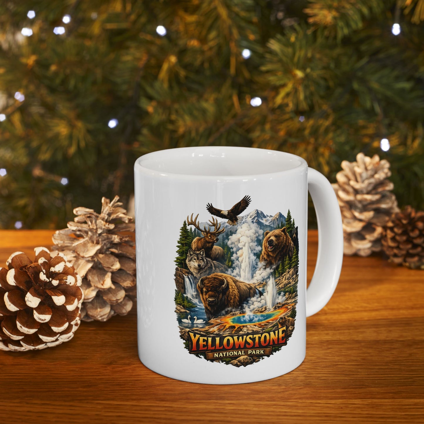 White mug with Yellowstone National Park design on a wooden surface with pinecones and a Christmas tree in the background.