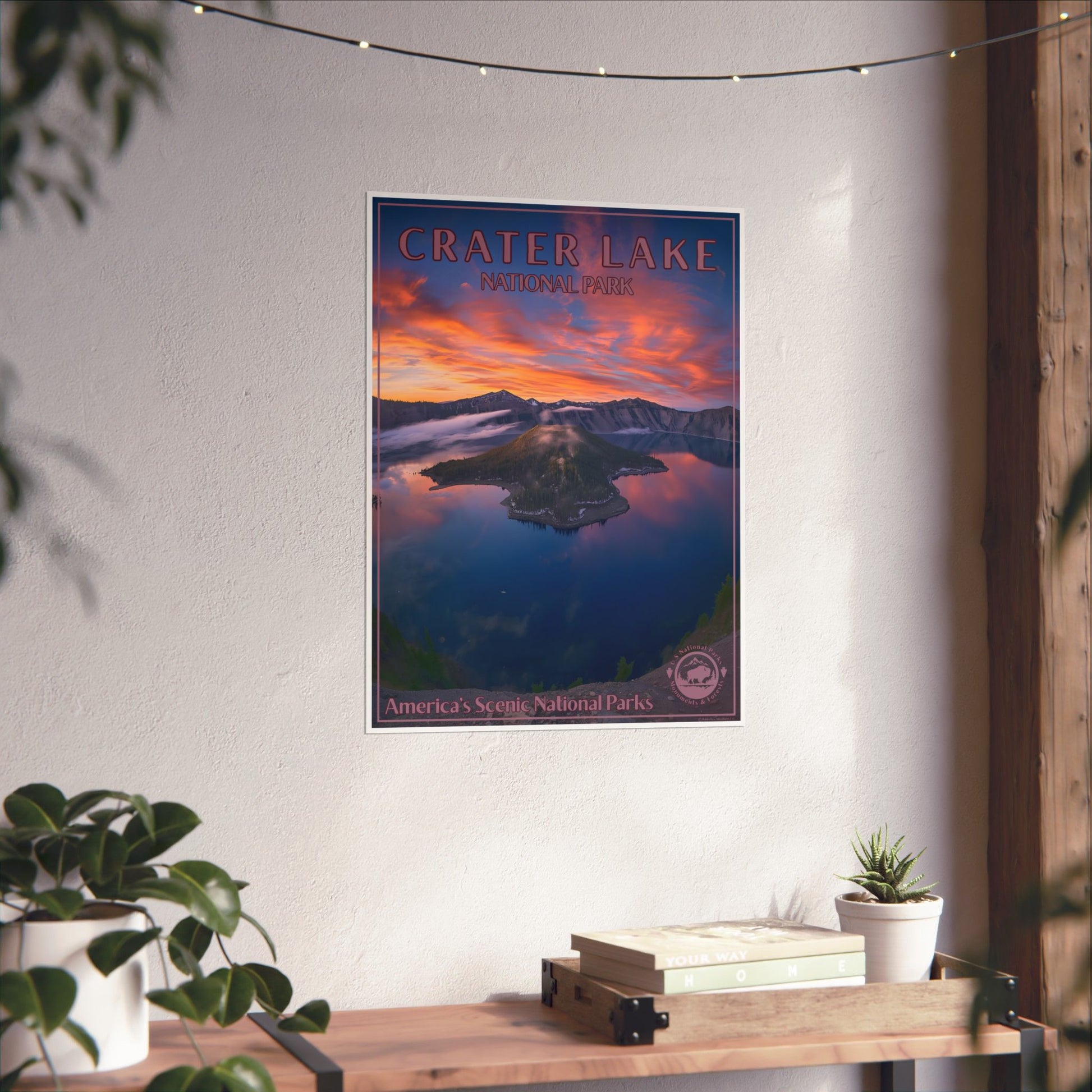 Poster of Crater Lake hanging on a wall above a wooden shelf with plants.