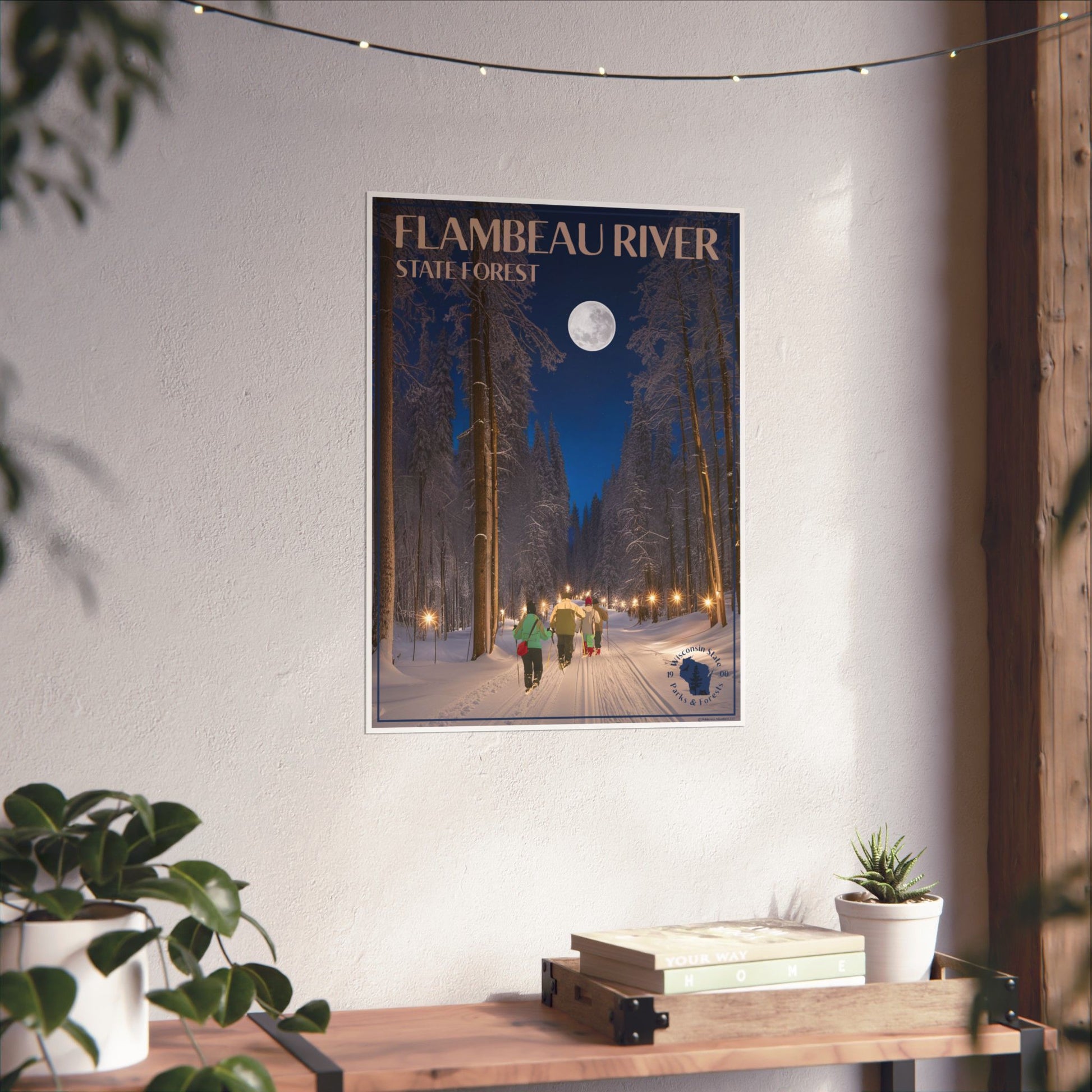 Poster of Flambeau River State Forest on a wall above a wooden desk with plants.