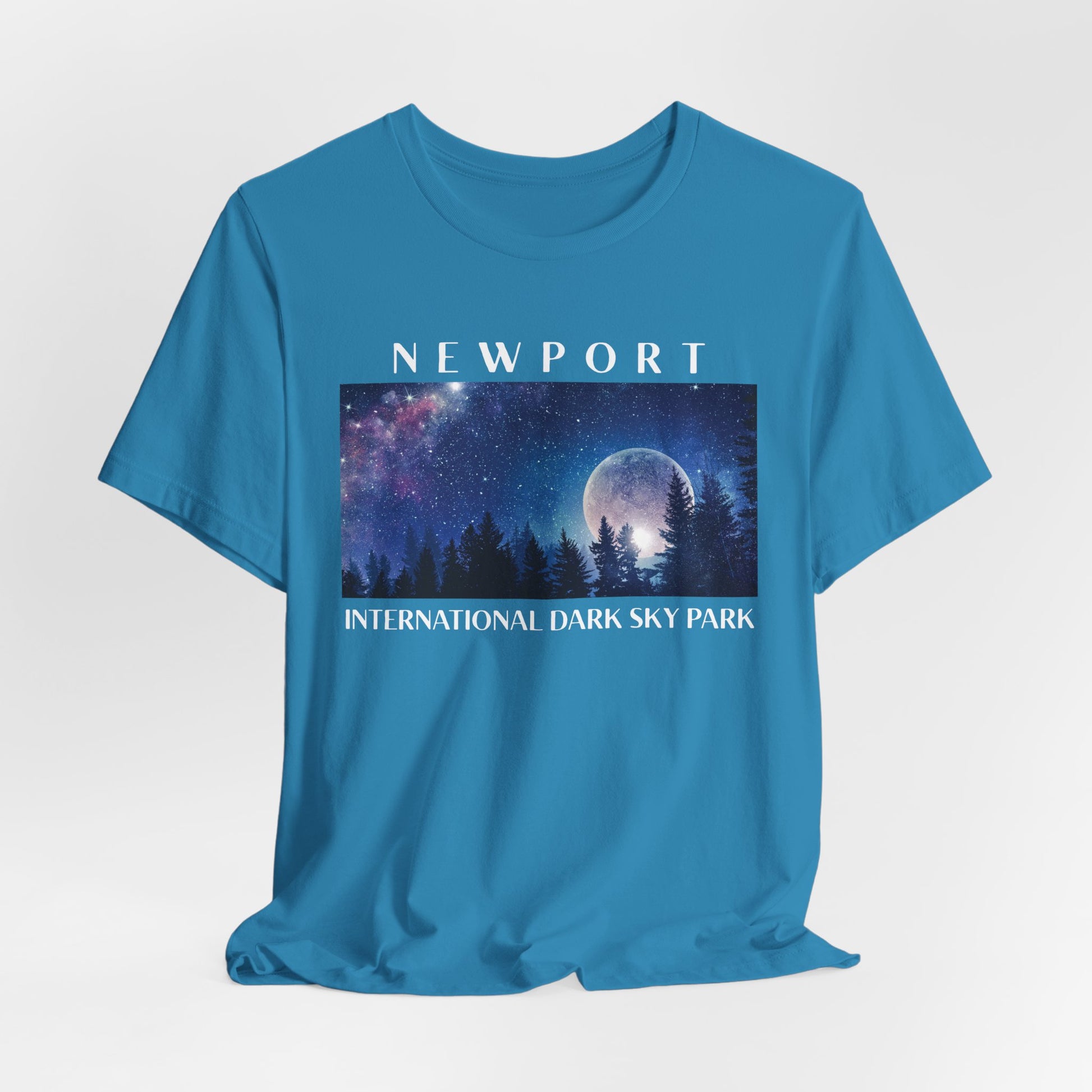 Aqua t-shirt with a graphic of a night sky and trees, featuring the text 'Newport International Dark Sky Park'.