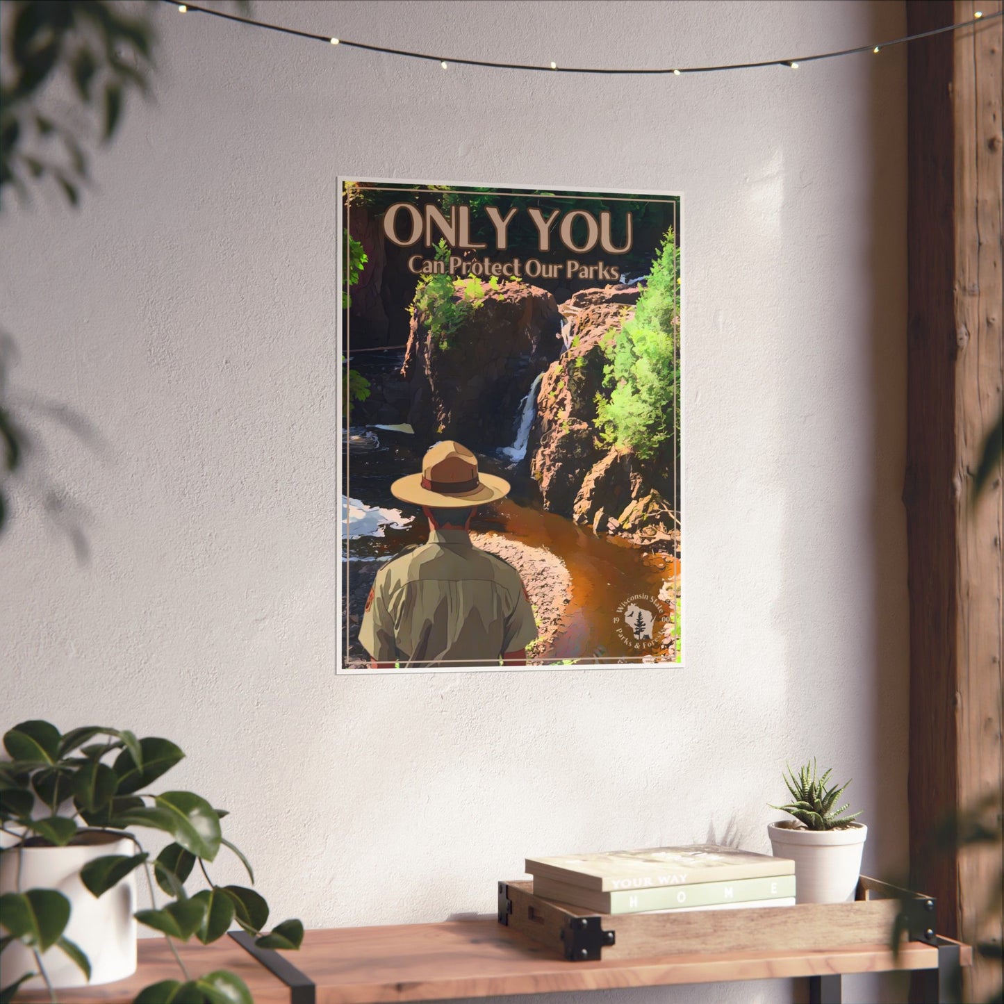 18 x 24” poster depicting a ranger overlooking copper Falls State Park hanging on a wall above a wood shelf with potted plants.