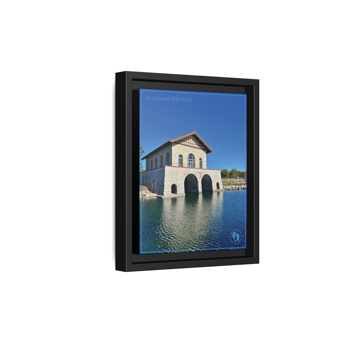 Angled profile of the Black Framed canvas print featuring the iconic stone boathouse at Rock Island State park set against a clear blue sky and blue water.  