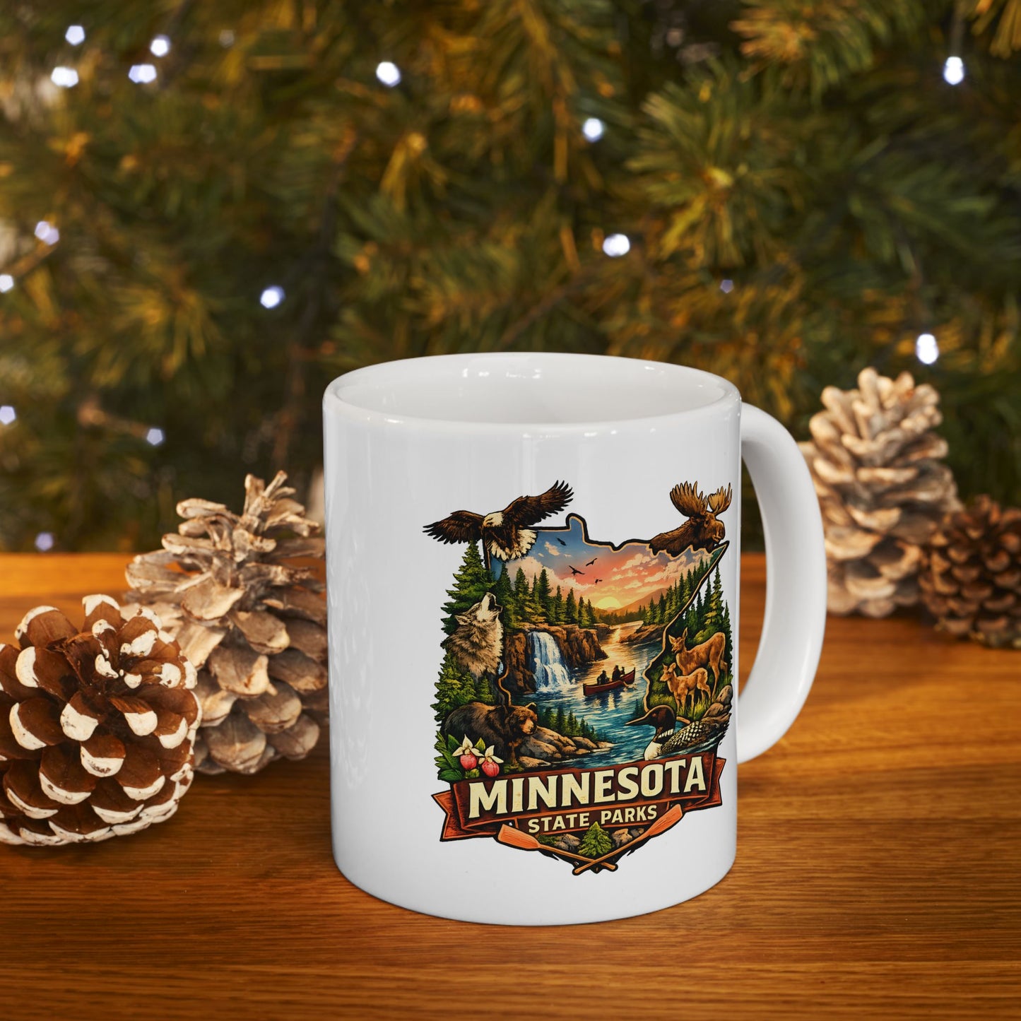 White mug with Minnesota State Parks design on a wooden surface with pinecones and a Christmas tree in the background.
