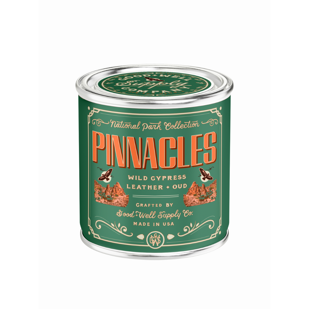 Pinnacles candle in a green tin with decorative text on a white background