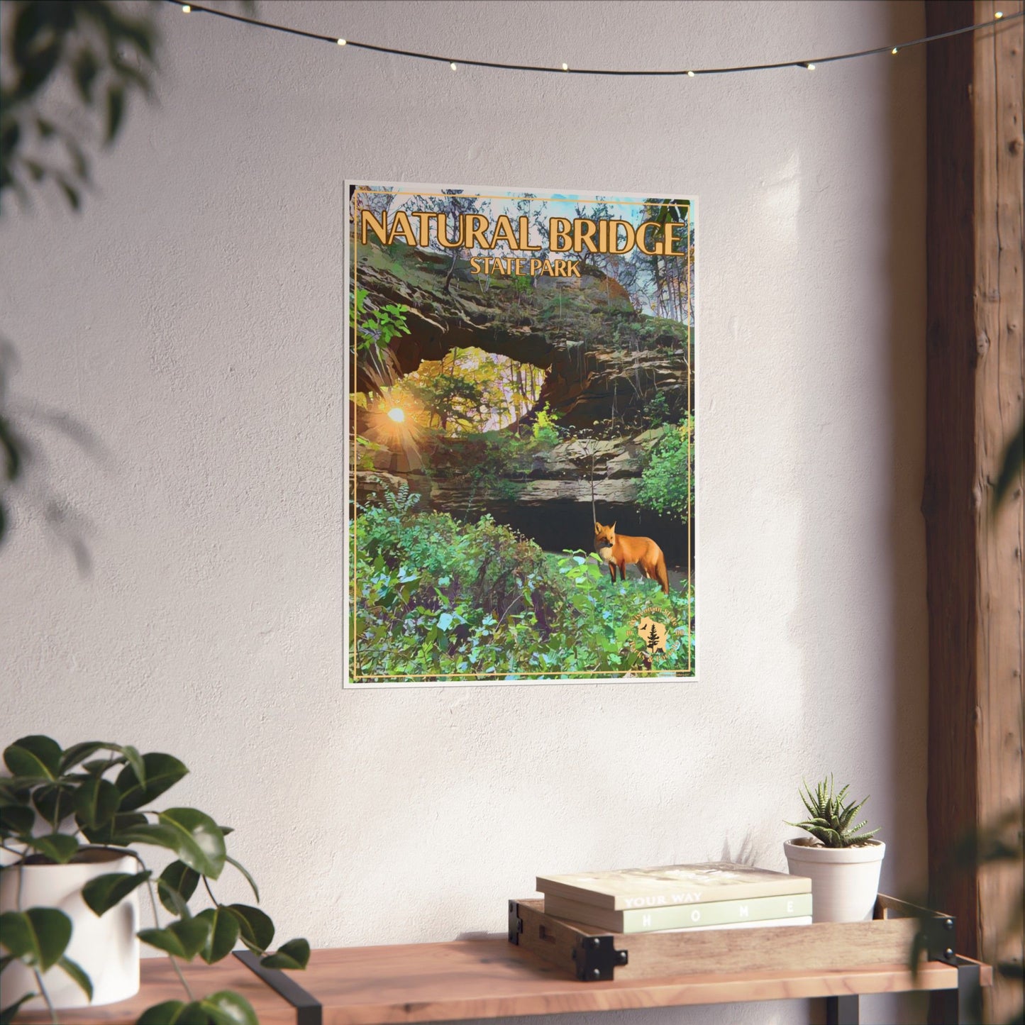 natural bridge poster depicting, a natural stone, arch, lush greenery, and a red fox hanging on a wall above a wood shelf and potted plants