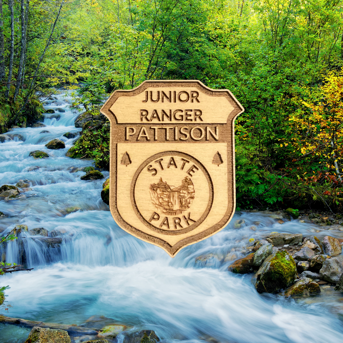 Wood badge featuring the text: “Junior Ranger Pattison State Park” and a waterfall icon with a scenic background of a stream and trees.