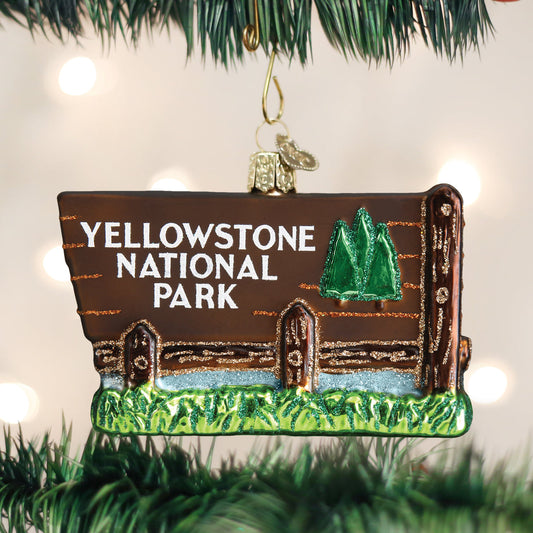 Glass Christmas ornament in shape of the Yellowstone National Park Entrance sign on a Christmas background. 