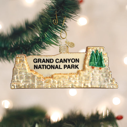 3-D glass ornament in the shape of the Grand Canyon national Park entrance sign against the festive background