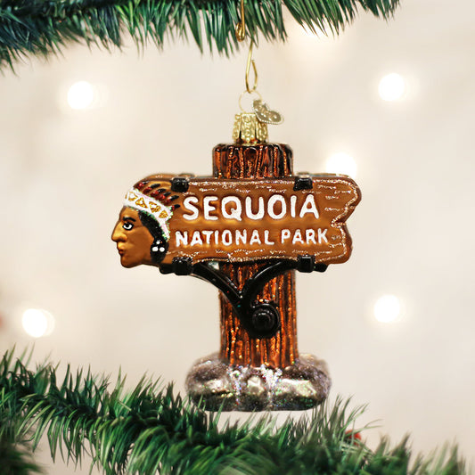 3D glass ornament in the shape of the sequoia national Park entrance sign against a festive background