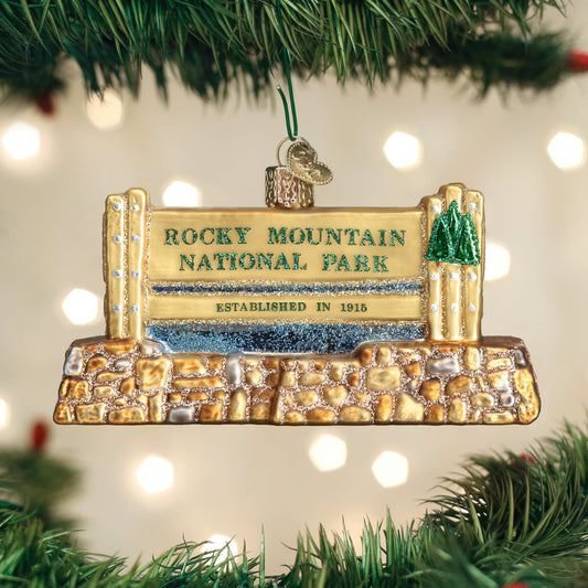 Glass ornament in the shape of the Rocky Mountain national Park entrance sign on a festive background.