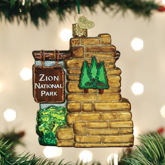 3-D glass ornament in the shape of the Zion national park entrance sign on a festive background.
