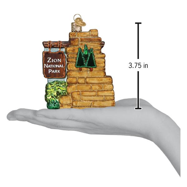 3-D glass ornament in the shape of the Zion national park entrance sign on a hand showing ornament size on a white background.