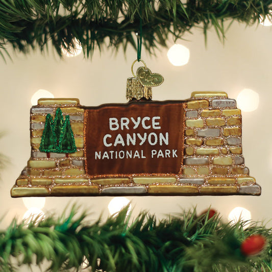 Handcrafted 3-D glass ornament in the shape of the Bryce Canyon national Park entrance sign on a festive background.