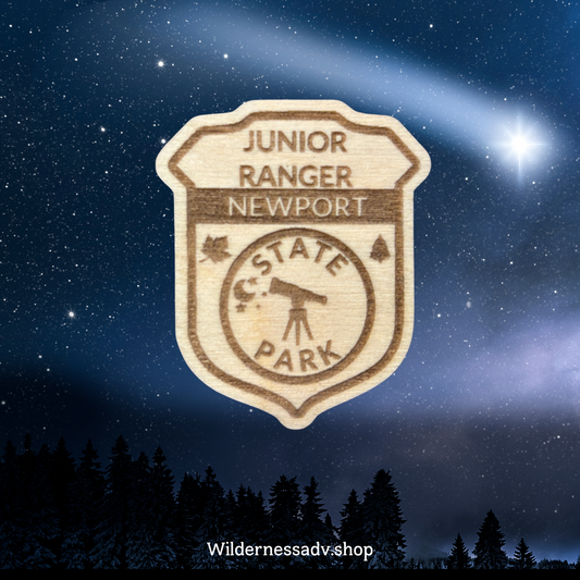 Wood Jr. Ranger badge with the text: Junior Ranger Newport State Park.  Photo background of a starry sky.