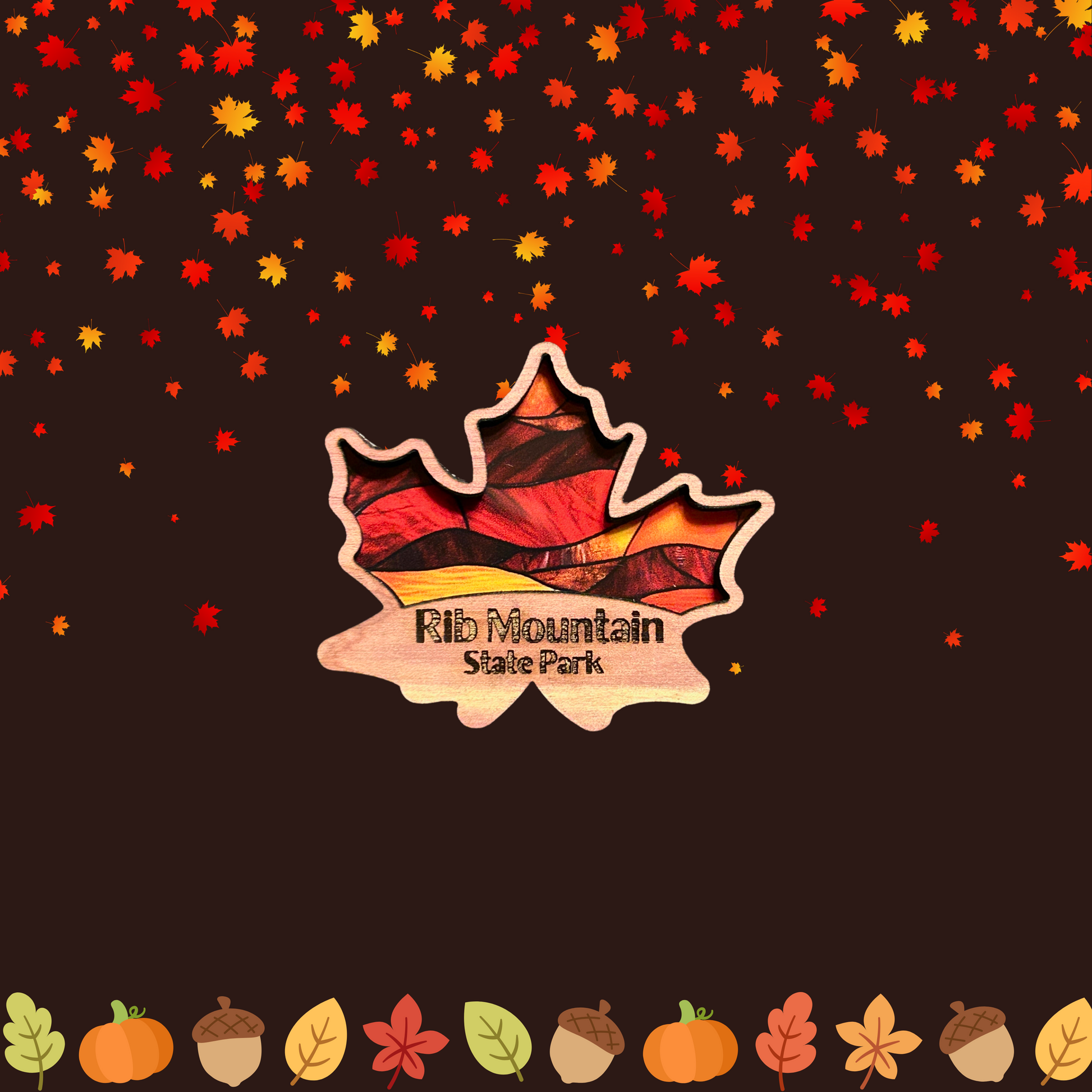 Cedar magnet in the shape of a maple leaf with a stained glass appearance and the Text “Rib Mountain State Park.”  Photo background: pumpkins, pinecones and falling leaves.