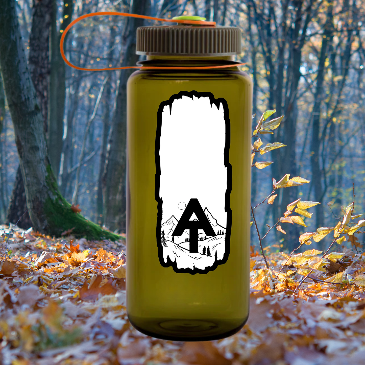 Weatherproof Appalachian Trail Blaze sticker with AT text and a scenic mountain design affixed to a Nalgene bottle sitting on a leaf covered forest floor.