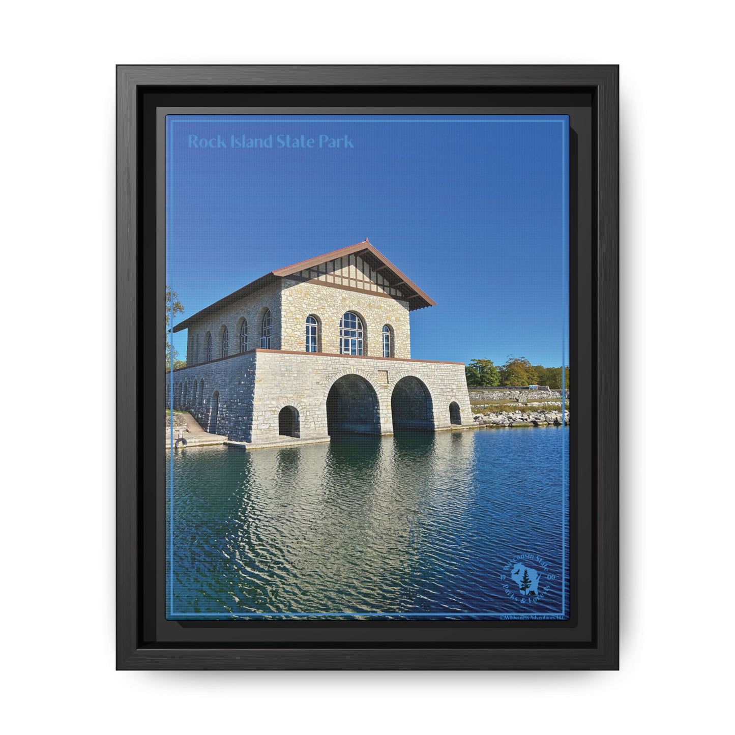 Black Framed canvas print featuring the iconic stone boathouse at Rock Island State park set against a clear blue sky and blue water.  