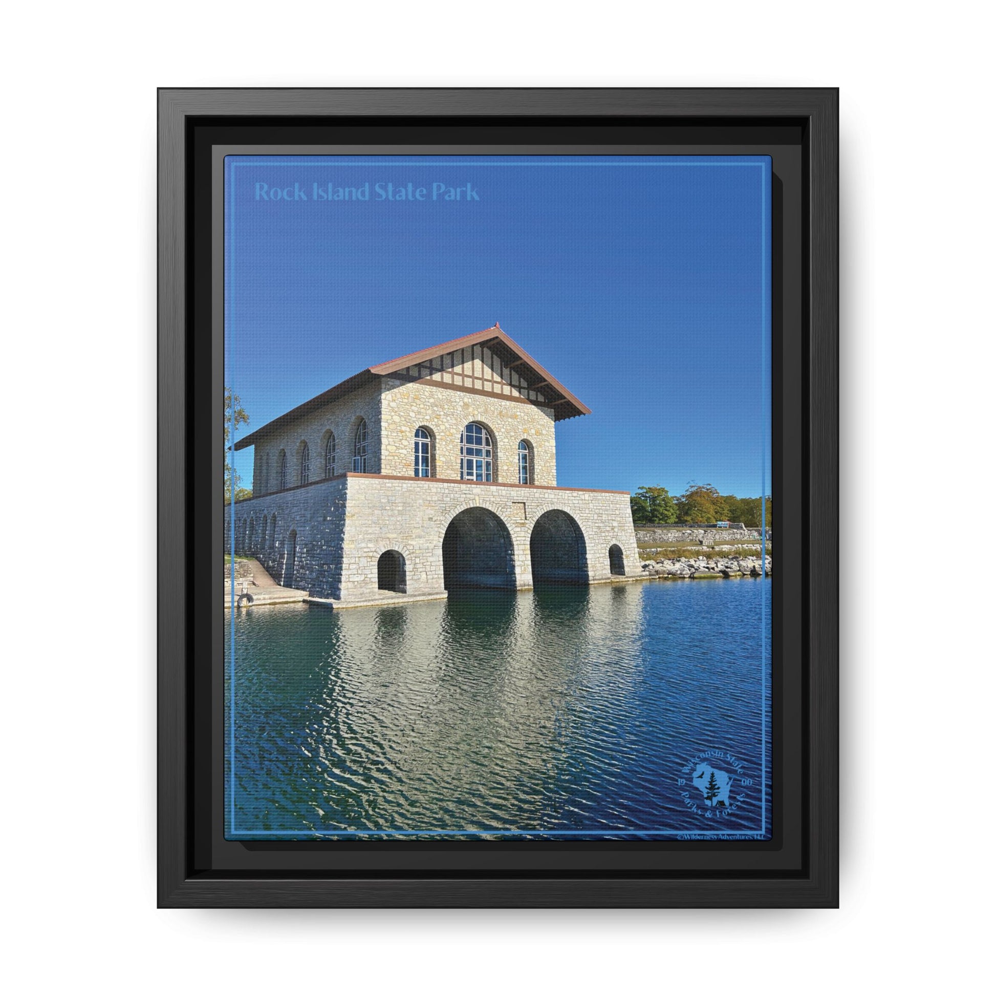 Black Framed canvas print featuring the iconic stone boathouse at Rock Island State park set against a clear blue sky and blue water.  