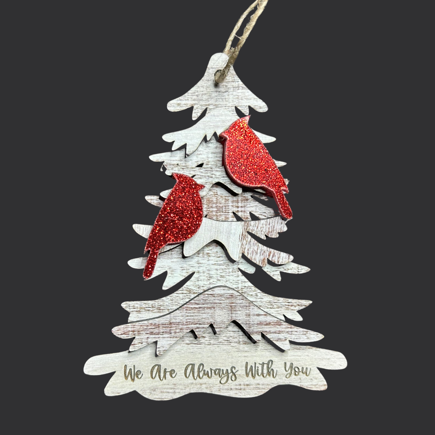 Two red glitter cardinals on a wood tree ornament with the text “we are always with you” on a dark background.